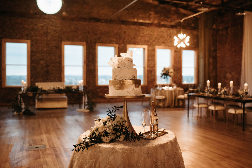 Two tiered cake with gold detail at indoor wedding reception