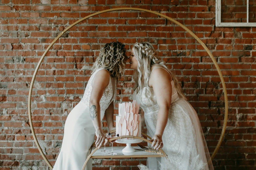 Brides kissing with cake at modern elopement in Tennessee