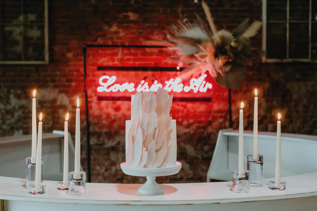 Modern cake with candles and neon sign at boho elopement