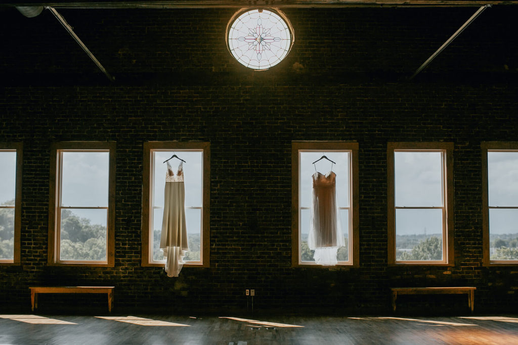 Boho modern wedding dresses hanging in window for intimate elopement