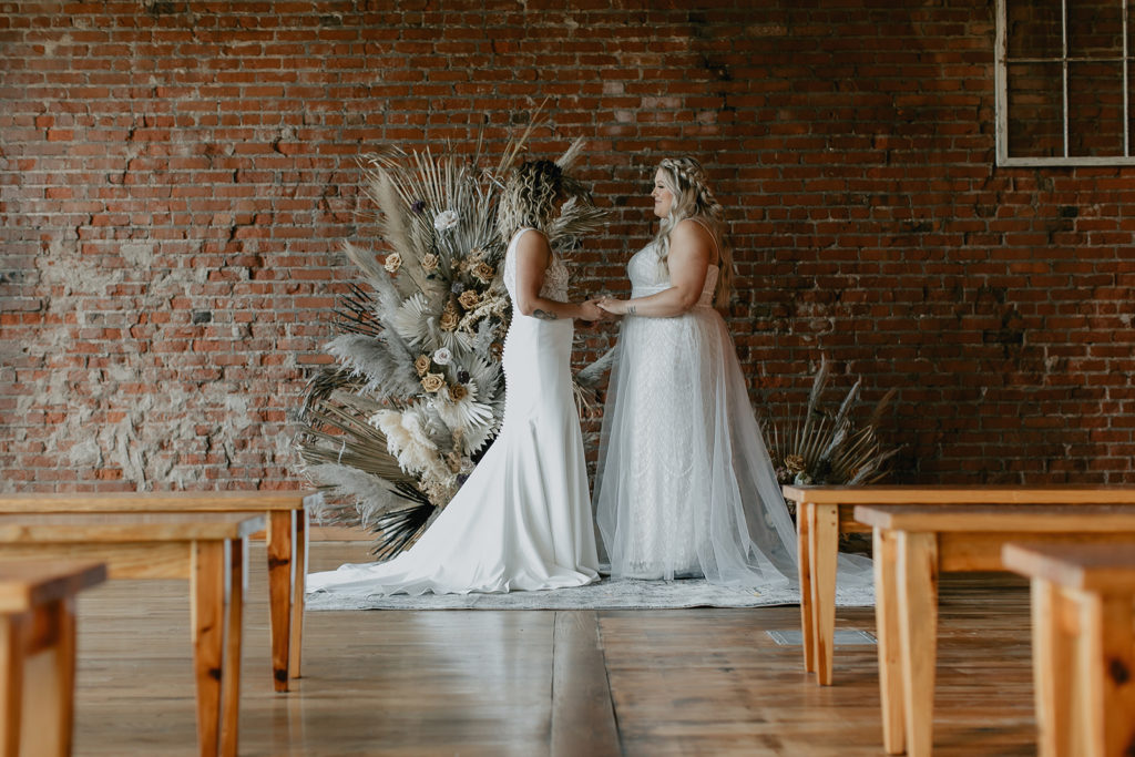 Brides holding hands at indoor wedding ceremony in Tennessee